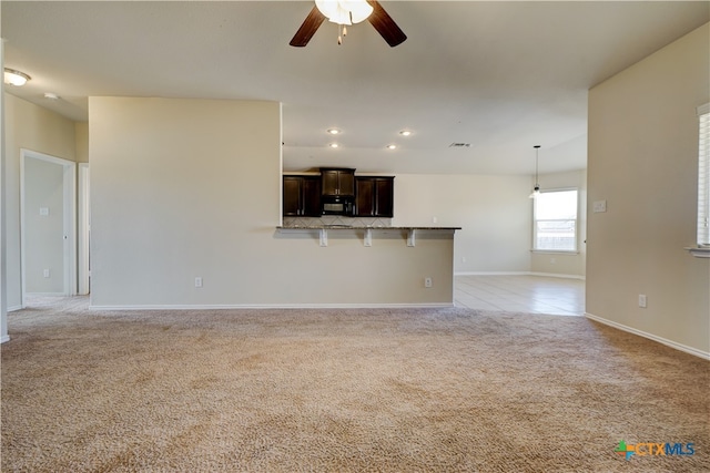 unfurnished living room featuring light carpet and ceiling fan