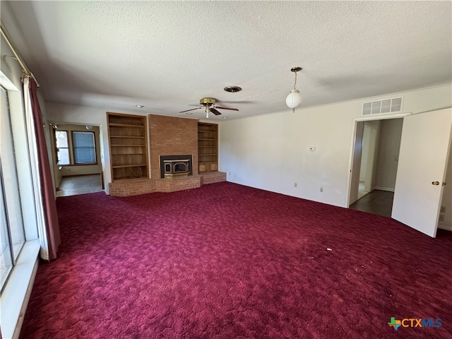 unfurnished living room featuring plenty of natural light, dark carpet, a textured ceiling, and ceiling fan