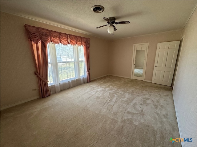 unfurnished room featuring a textured ceiling, ceiling fan, crown molding, and light carpet