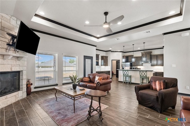 8306 Callahan Dr, Killeen, TX 76542 - living room with a raised ceiling, crown molding, ceiling fan, a stone fireplace, and wood finish floors