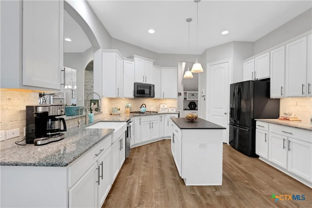 kitchen featuring tasteful backsplash, black appliances, a center island, and white cabinets