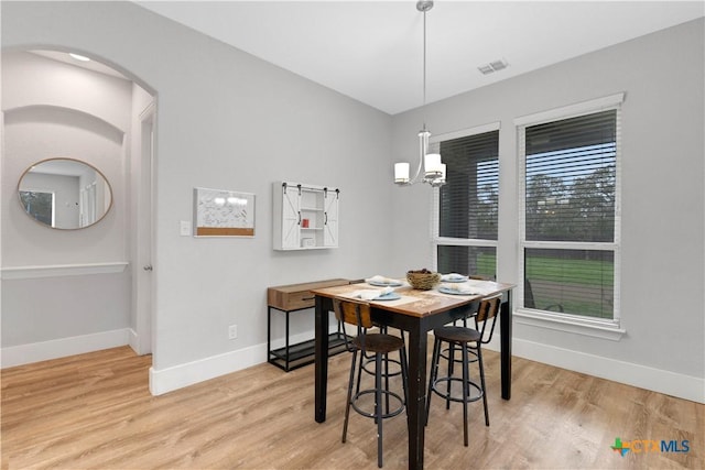 dining area with light wood finished floors, visible vents, a chandelier, and baseboards