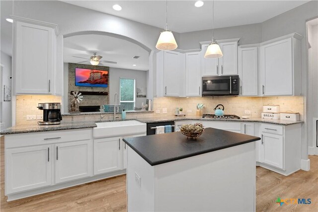 kitchen with decorative backsplash, stainless steel gas stovetop, light wood finished floors, and a sink