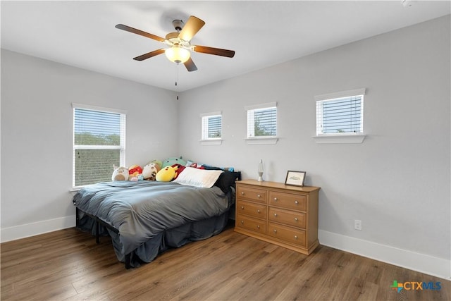 bedroom featuring a ceiling fan, light wood-style flooring, and baseboards