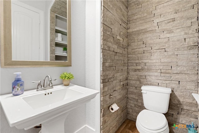 bathroom featuring wood finished floors, toilet, and a sink