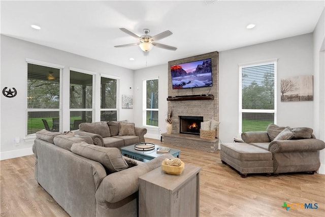 living area featuring ceiling fan, baseboards, light wood-type flooring, recessed lighting, and a stone fireplace