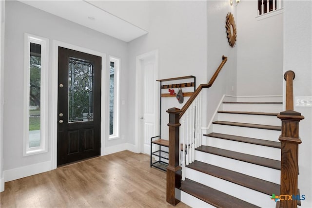 foyer entrance with stairway, wood finished floors, and baseboards
