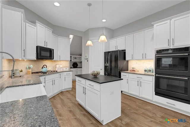 kitchen featuring white cabinets, black appliances, decorative backsplash, and a sink