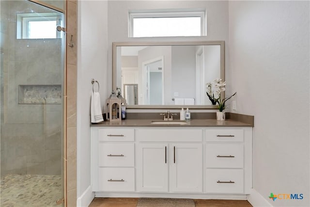 bathroom with a shower stall, wood finished floors, vanity, and baseboards
