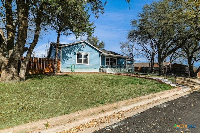 ranch-style home with a front yard and fence