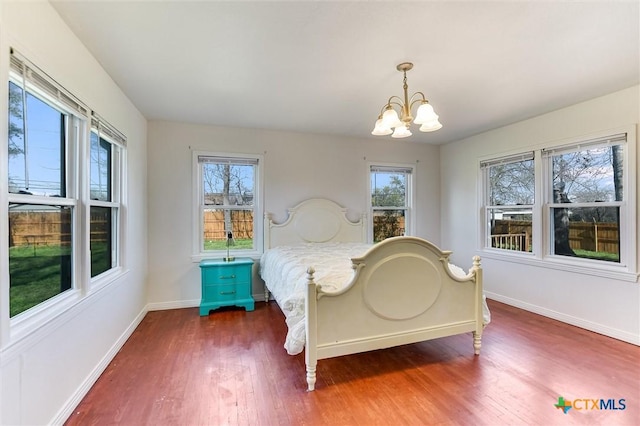 bedroom featuring wood finished floors, baseboards, and a chandelier