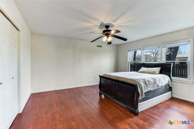 bedroom with visible vents, baseboards, wood finished floors, and a ceiling fan