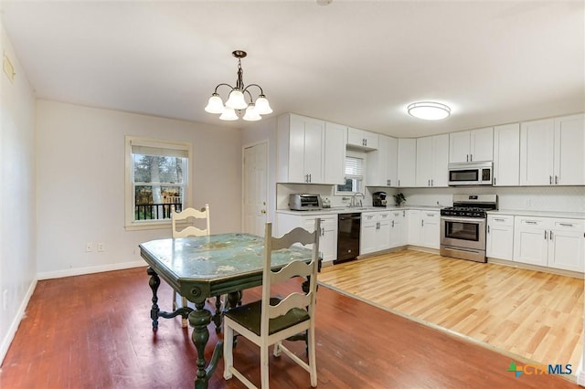 kitchen with light wood-type flooring, a sink, stainless steel range with gas cooktop, white microwave, and dishwasher