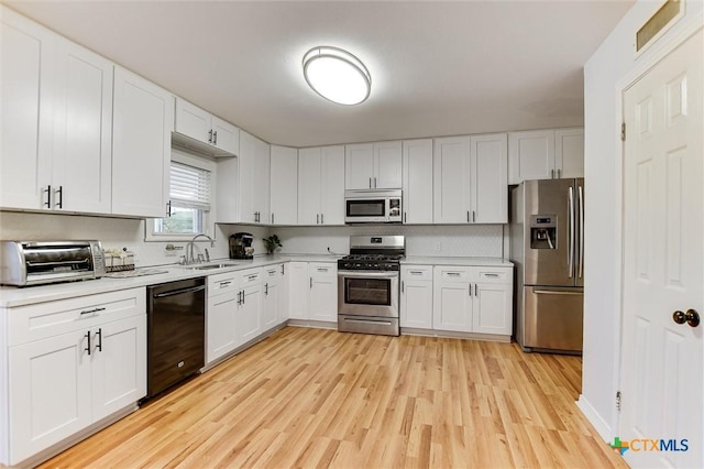 kitchen with a sink, stainless steel appliances, a toaster, light wood-style floors, and light countertops