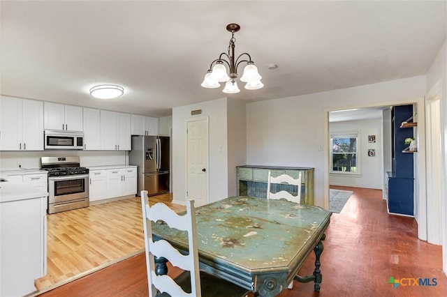 dining room featuring an inviting chandelier, visible vents, and light wood-type flooring