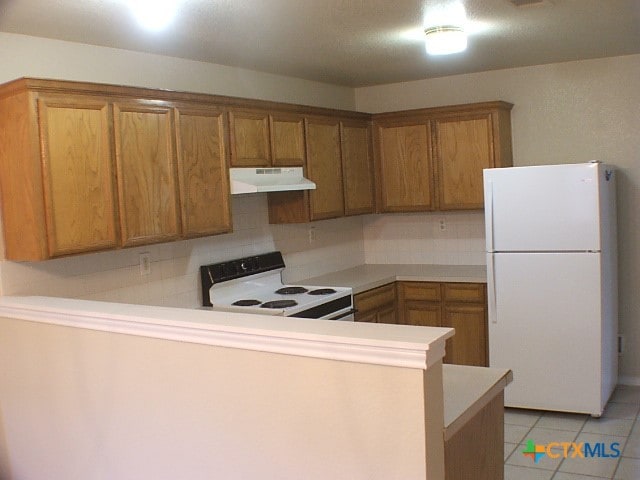 kitchen with backsplash, kitchen peninsula, light tile patterned floors, and white appliances