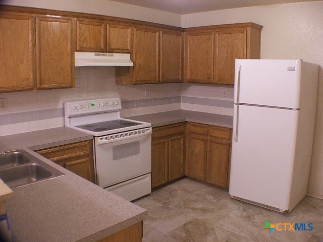 kitchen featuring backsplash, sink, and white appliances