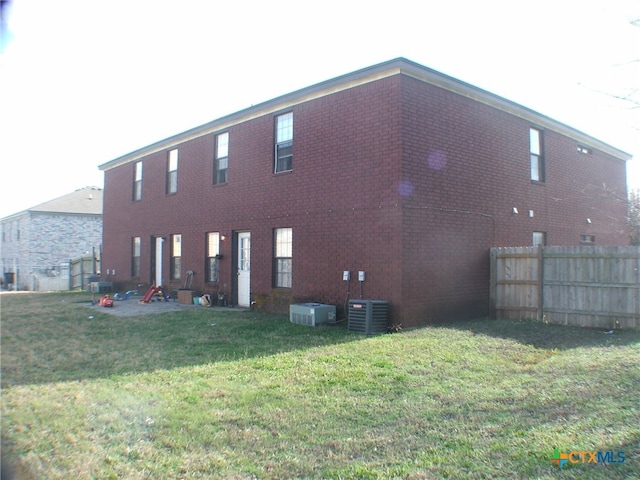 rear view of property featuring central AC and a lawn