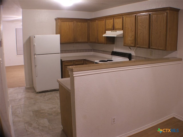 kitchen featuring backsplash, white appliances, and kitchen peninsula