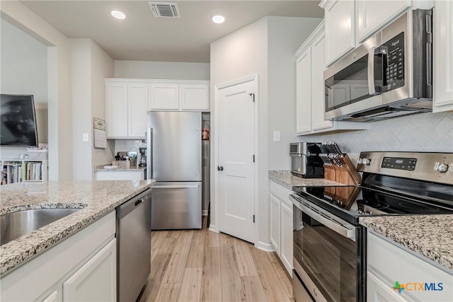 707 Winscott Ave, Temple, TX 76502 - kitchen featuring stainless steel appliances, white cabinets, recessed lighting, decorative backsplash, and light wood-style floors