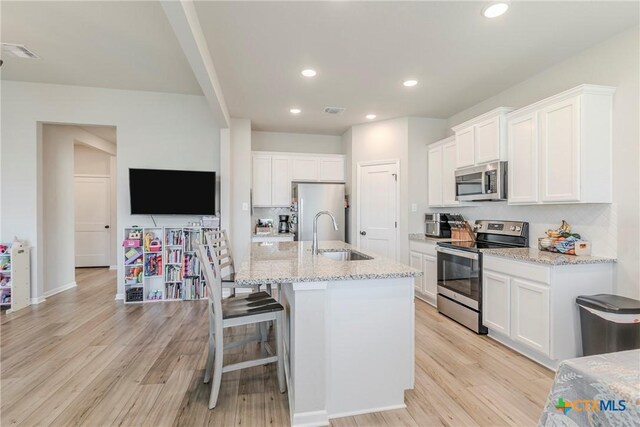 707 Winscott Ave, Temple, TX 76502 - kitchen with stainless steel appliances, a sink, light wood-type flooring, white cabinetry, and light stone countertops