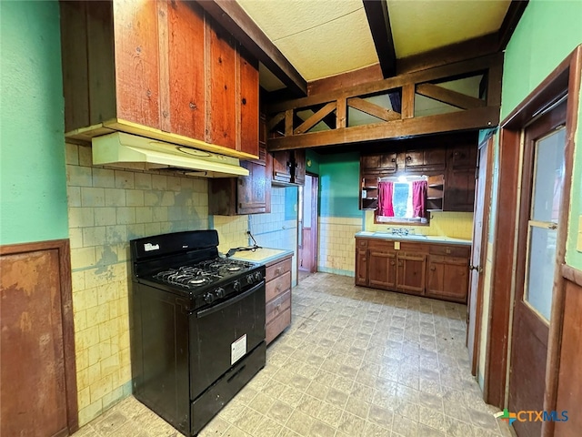 kitchen with backsplash, beamed ceiling, sink, and black range with gas cooktop