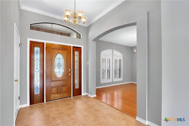 foyer with an inviting chandelier, baseboards, ornamental molding, and wood finished floors