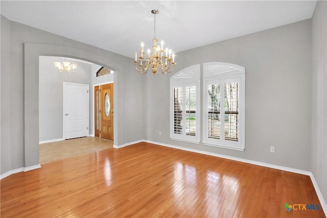 unfurnished room with light wood-style floors, baseboards, and a chandelier