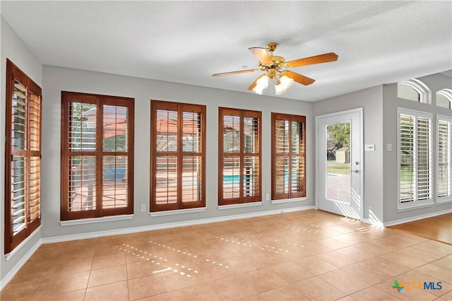 entryway featuring a ceiling fan, a wealth of natural light, a textured ceiling, and light tile patterned floors