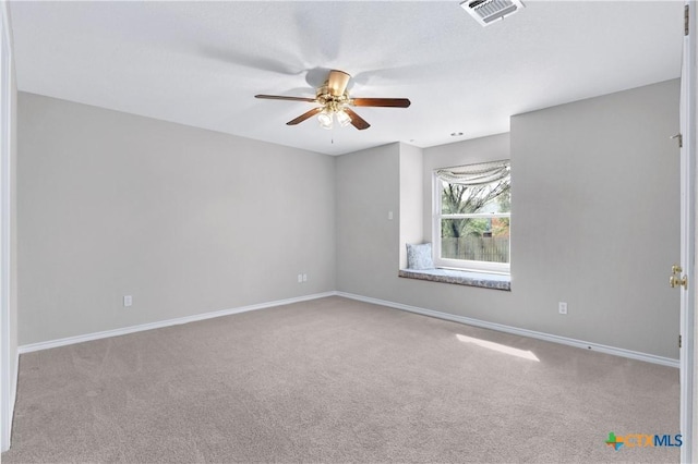 carpeted empty room featuring baseboards, visible vents, and a ceiling fan