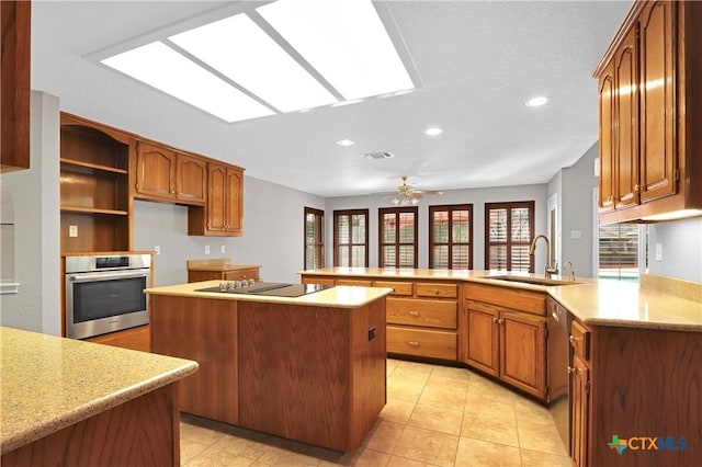 kitchen featuring visible vents, a kitchen island, appliances with stainless steel finishes, a peninsula, and a sink