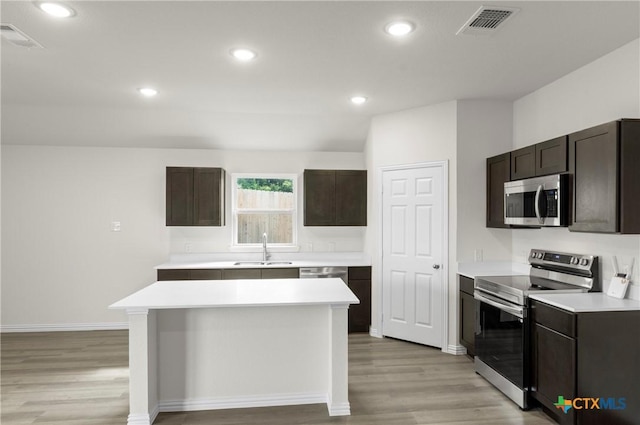 3812 Keller Rd, Temple, TX 76504 - kitchen featuring appliances with stainless steel finishes, light wood-style floors, light countertops, dark brown cabinets, and a kitchen island
