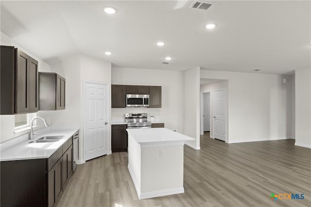 3812 Keller Rd, Temple, TX 76504 - kitchen with stainless steel appliances, a center island, light countertops, light wood-type flooring, and dark brown cabinetry