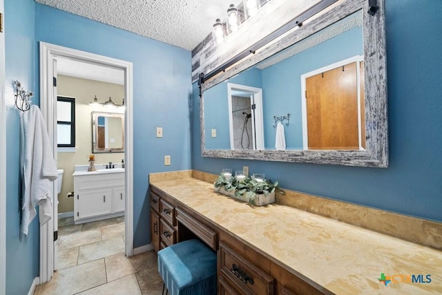 bathroom featuring a textured ceiling, a shower, vanity, and baseboards