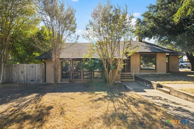 single story home featuring a front yard, fence, and brick siding