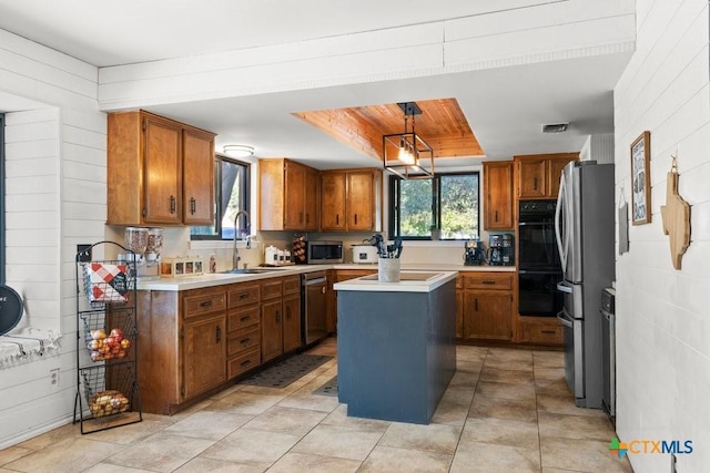 kitchen with brown cabinetry, a kitchen island, stainless steel appliances, light countertops, and a sink