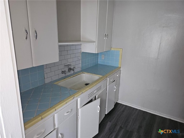 kitchen with a sink, tile counters, white cabinetry, and dark wood-style flooring