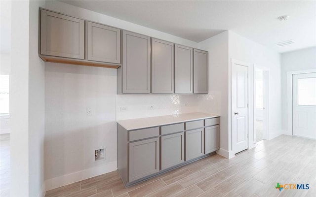 513 Lina Way, Seguin, TX 78155 - kitchen with gray cabinetry, baseboards, light wood-type flooring, backsplash, and light countertops