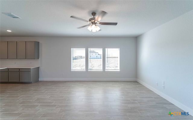 unfurnished living room featuring light wood-type flooring, a textured ceiling, and ceiling fan