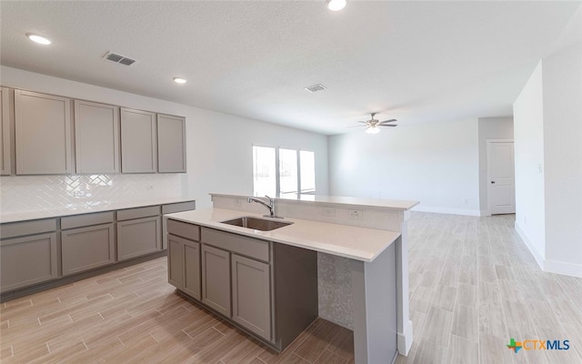 kitchen with a textured ceiling, light wood-type flooring, sink, and ceiling fan