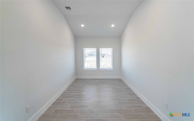 unfurnished room featuring light hardwood / wood-style floors and lofted ceiling