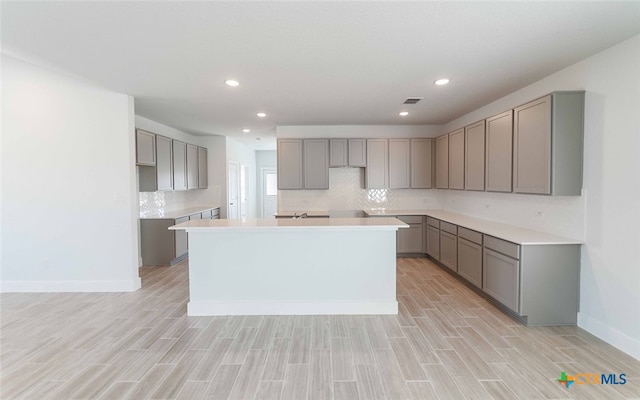 kitchen featuring gray cabinets, light hardwood / wood-style flooring, and a center island