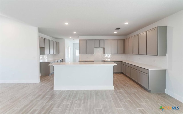 513 Lina Way, Seguin, TX 78155 - kitchen featuring gray cabinets, a kitchen island, backsplash, light wood-type flooring, and recessed lighting