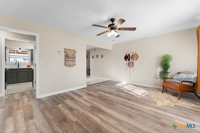 unfurnished room with ceiling fan, sink, and light wood-type flooring