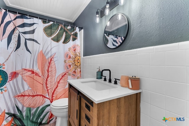 bathroom with tile walls, toilet, and vanity