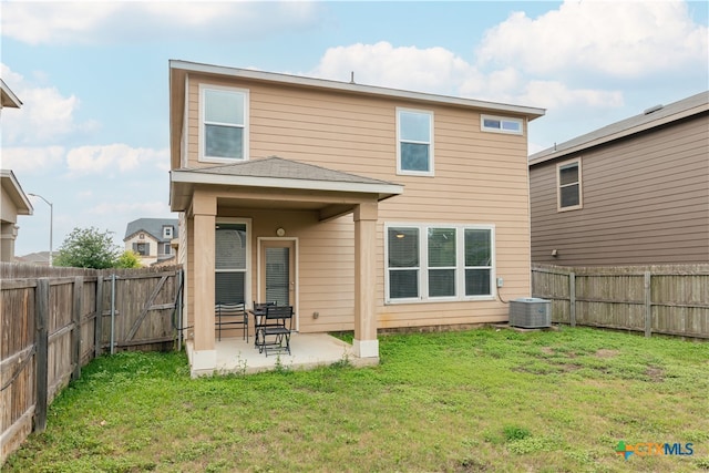 rear view of house with a lawn, cooling unit, a patio area, and a fenced backyard