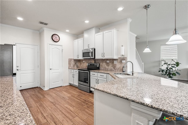 kitchen with a sink, crown molding, a peninsula, white cabinets, and appliances with stainless steel finishes