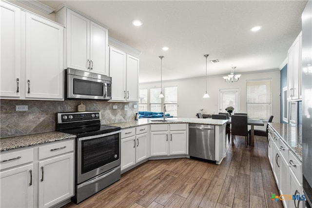 kitchen featuring white cabinetry, decorative backsplash, a sink, stainless steel appliances, and a notable chandelier