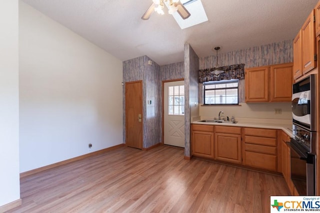 121 S Scenic Loop, Canyon Lake, TX 78133 - kitchen with oven, wallpapered walls, a skylight, a sink, and light countertops