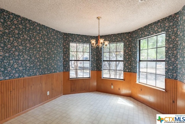 121 S Scenic Loop, Canyon Lake, TX 78133 - unfurnished dining area featuring a wainscoted wall, a chandelier, a textured ceiling, and wallpapered walls